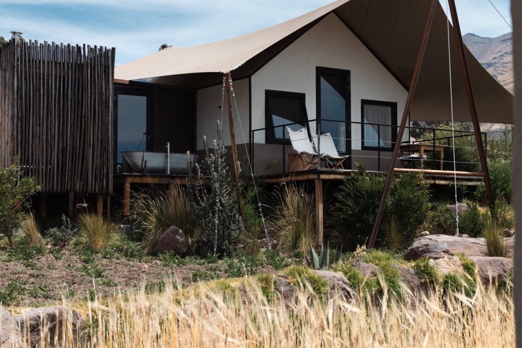 Luxury glamping lodge with private terrace and canvas roof set in a mountainous landscape.