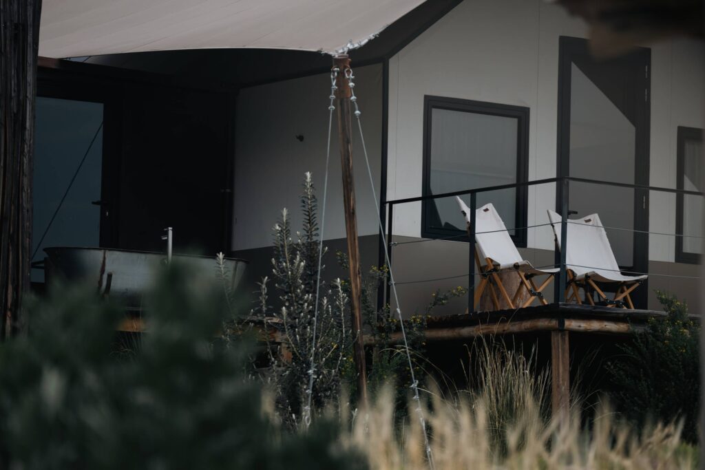 Luxury glamping lodge with outdoor bathtub and private deck in a natural setting.