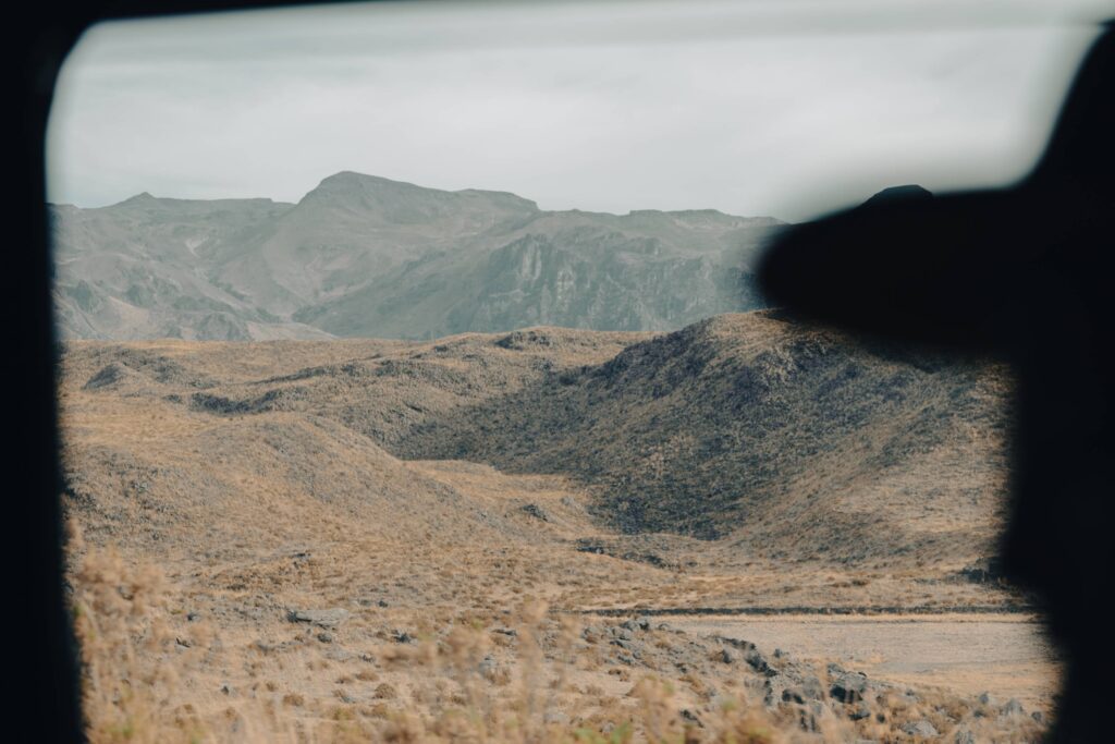 Mountain landscape viewed through a vehicle window during a remote road journey.