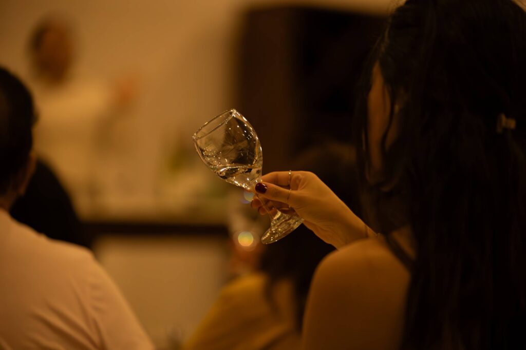 Close-up of woman holding a wine glass in a softly lit, intimate setting.